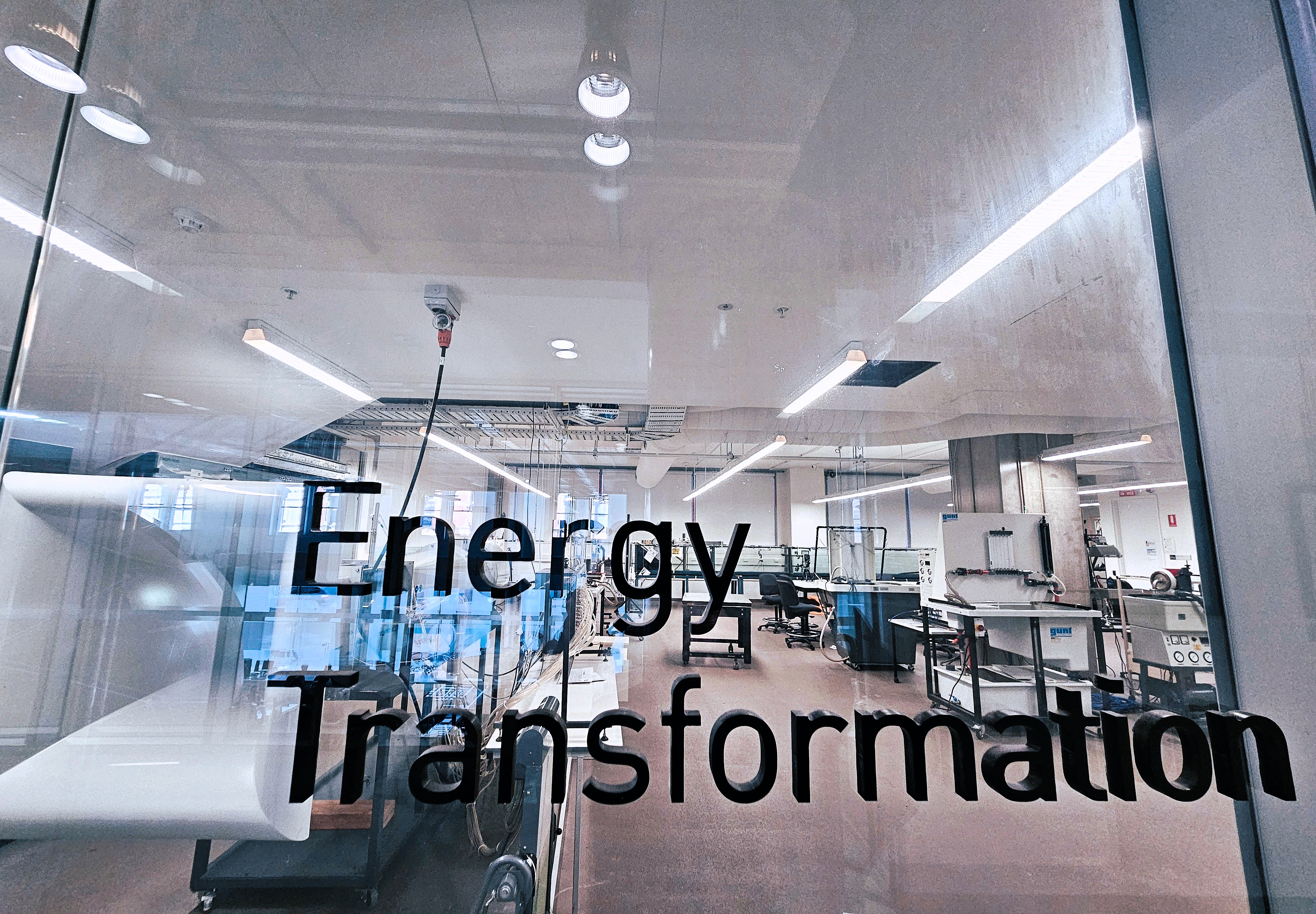 The front of the lab at Swinburne - A glass window pane with the Title Energy Transformation written in black typeset on the window